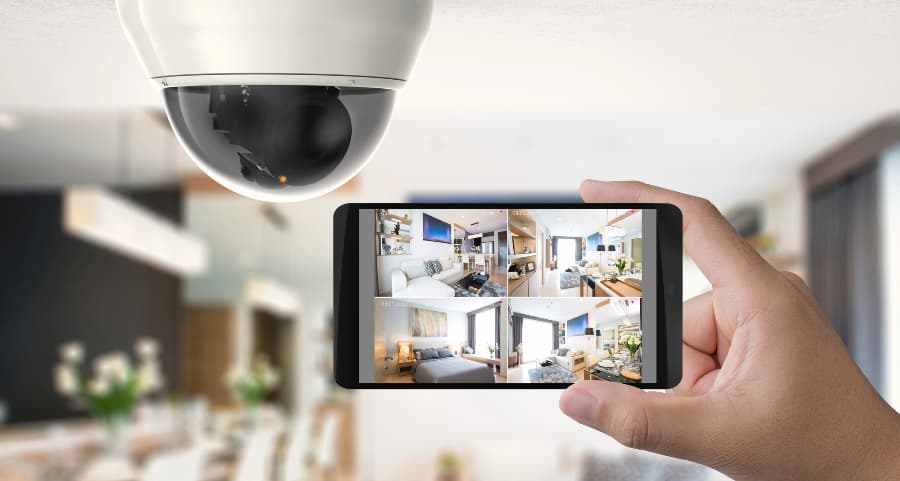 Homeowner holding smartphone with video feed from security cameras in Santa Clarita