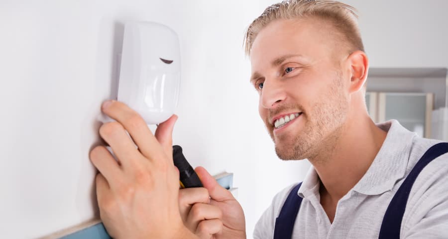 Man installing a motion sensor in a living area